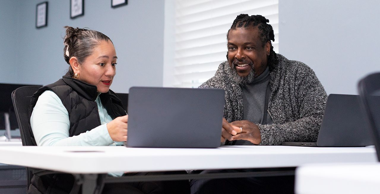 Two adult students using computers in a computer lab